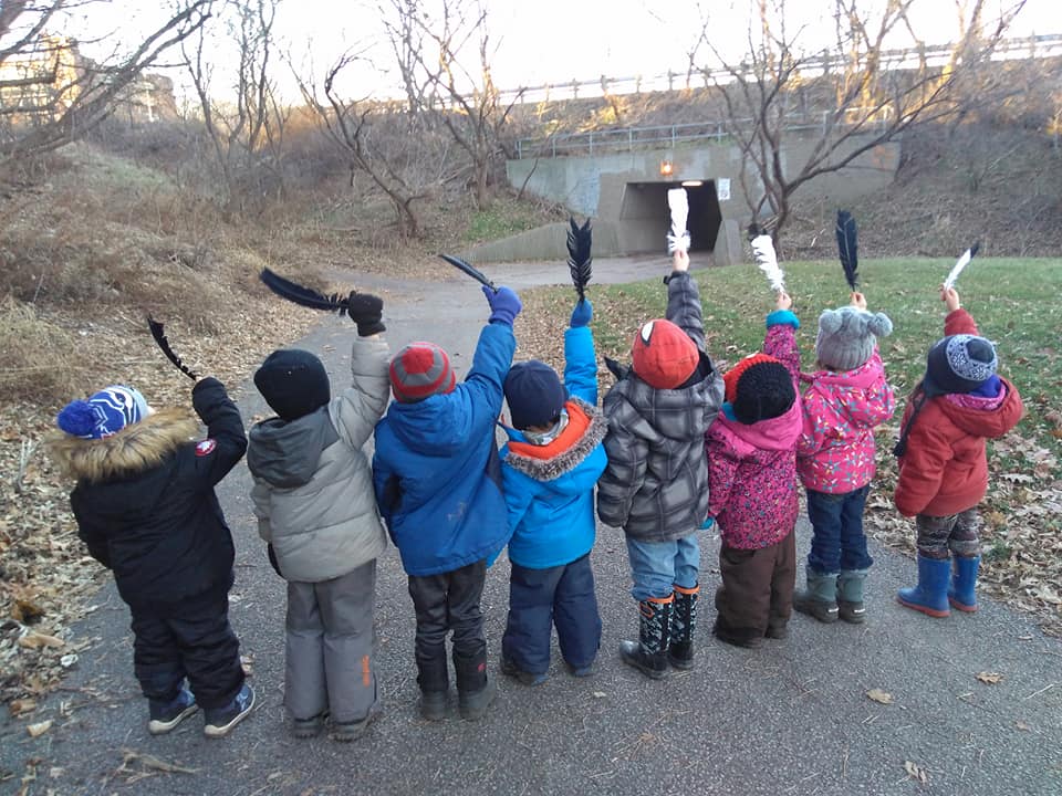 children raising up feathers in their hands on a trail